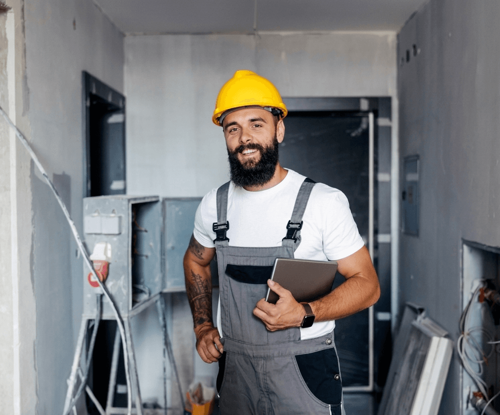 Smiling contractor in a hard hat checking install notes on a tablet